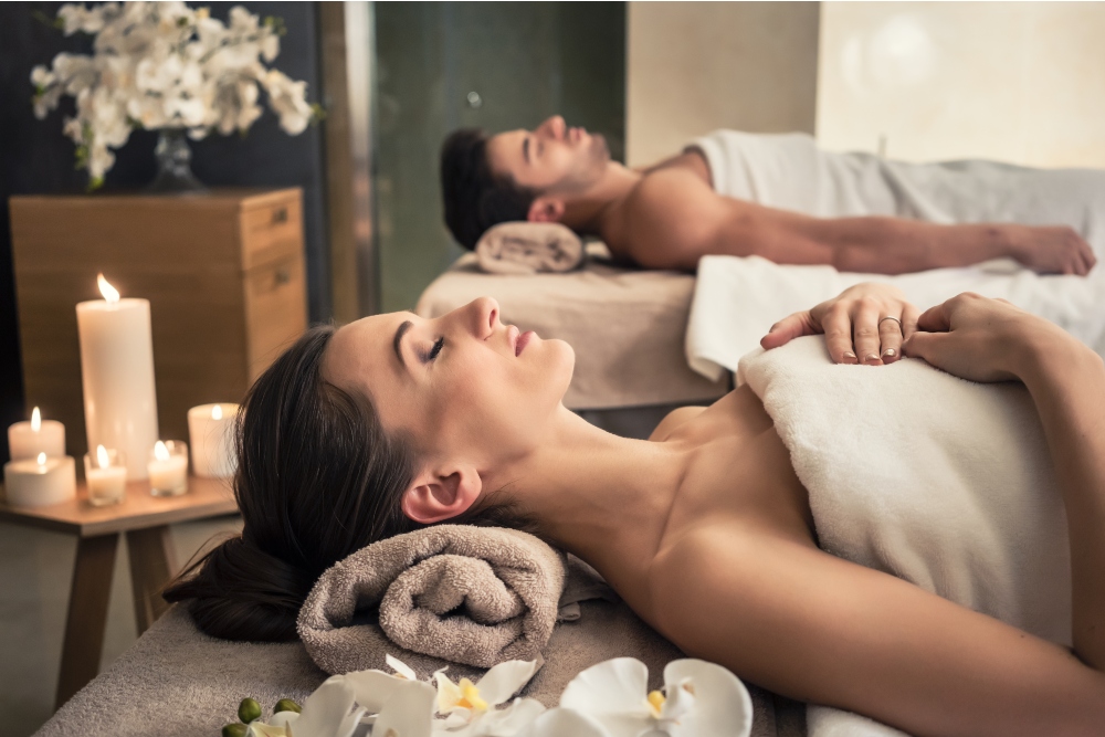 Young man and woman lying down on massage beds at luxury spa and wellness center