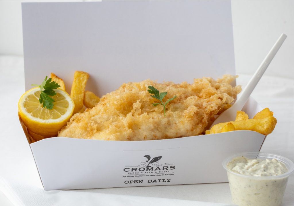 Fish and chips in a carton on a white background